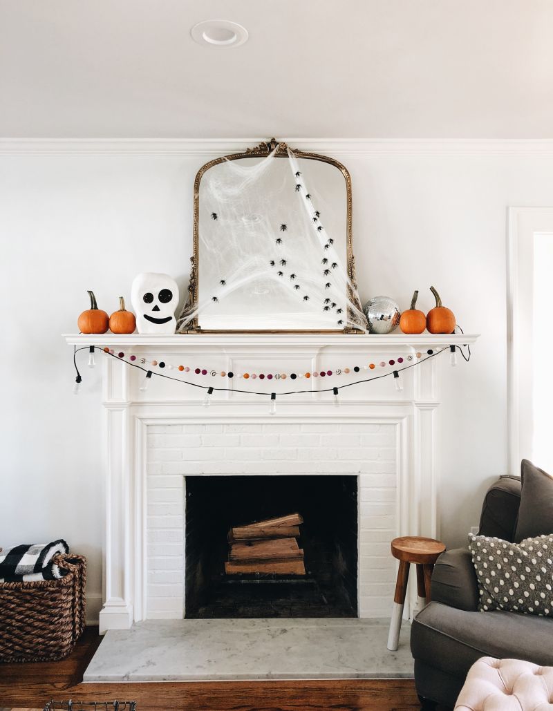 decorate fireplace mantel with spider web and mirror and mini pumpkins 