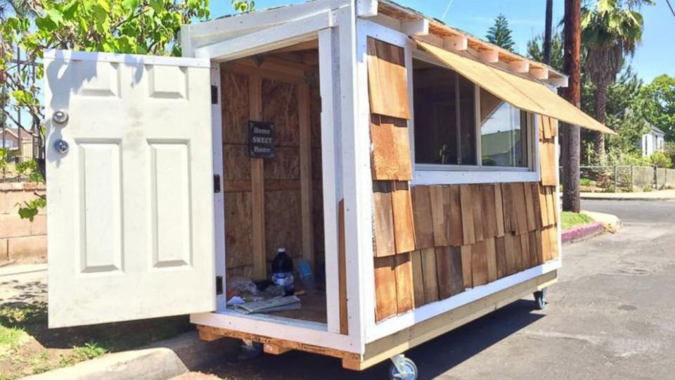 Tiny House features door with lock and sliding windows.