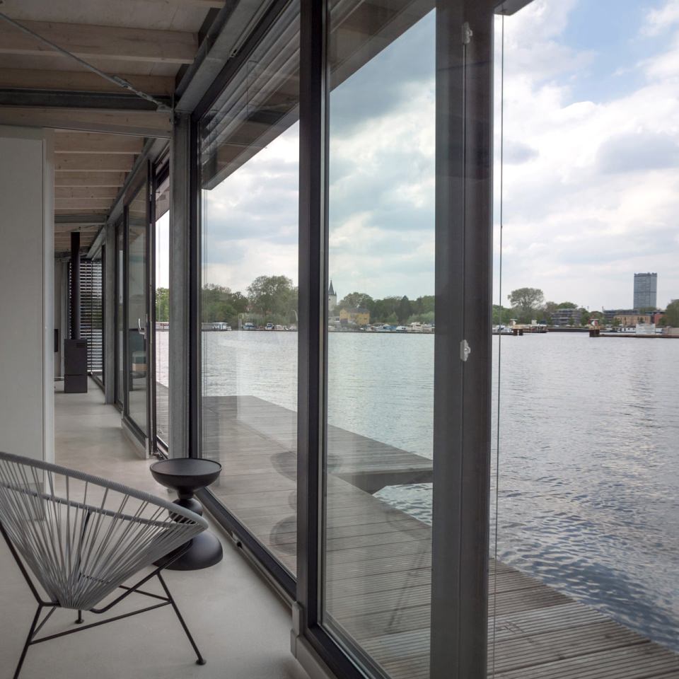 The front structure of the houseboat is built with windows and opens to the bay