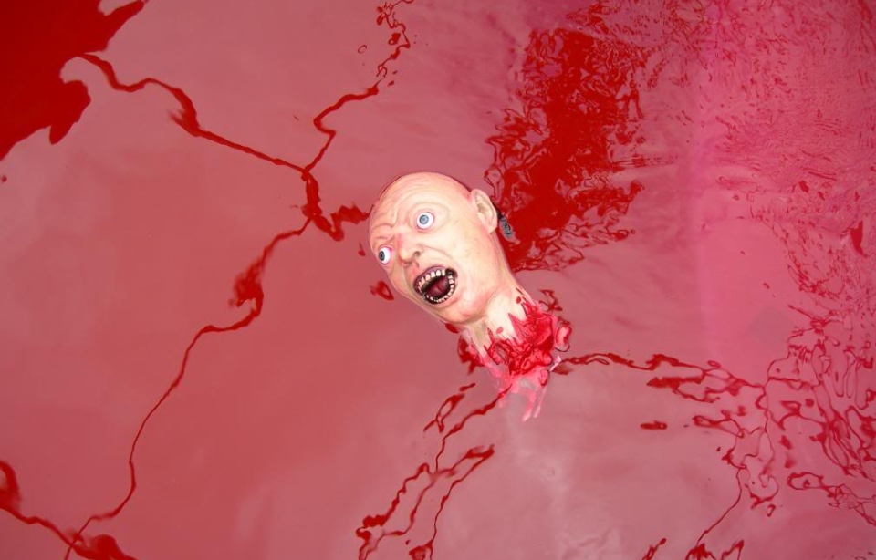 Decapitated Zombie Head in a pool with red color water look like blood  