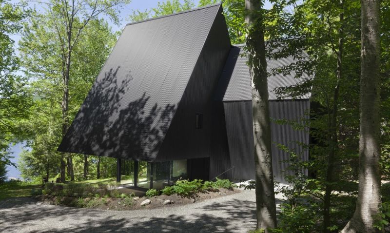 Strange black colored house among woods by Jean Verville