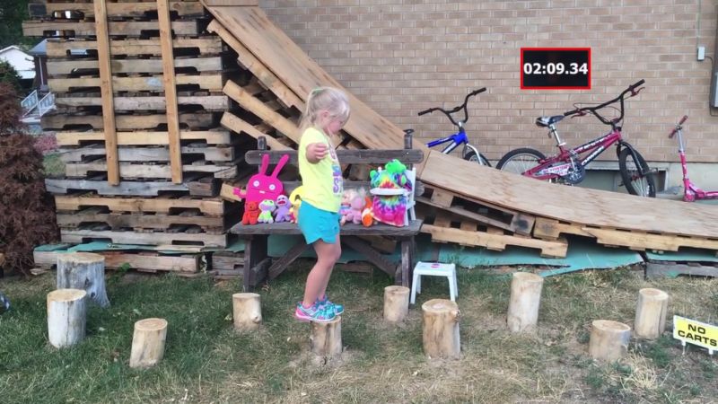 Little girl balanced on round wooden logs 