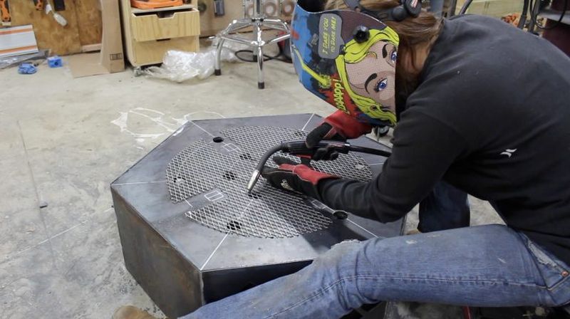 Attaching an expanded metal sheet over drain holes of the fire pit 