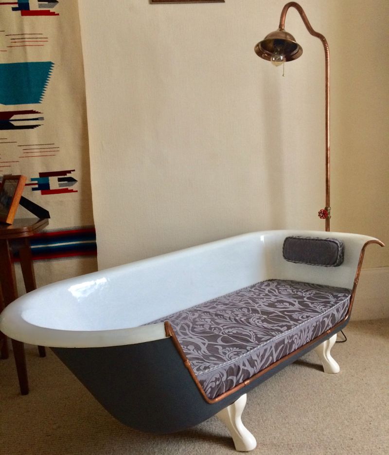 Old bathtub transformed into a sofa with brass lining 