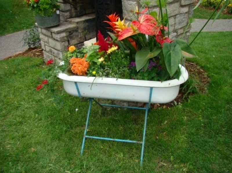 Old baby bathtub into planter on metal stand  