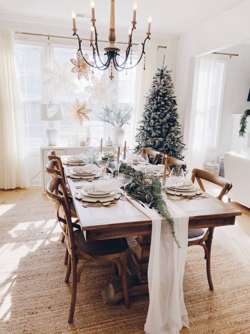 Christmas dining tablescape with a white table runner, olive and eucalyptus garland, glass candle holders and vintage glassware