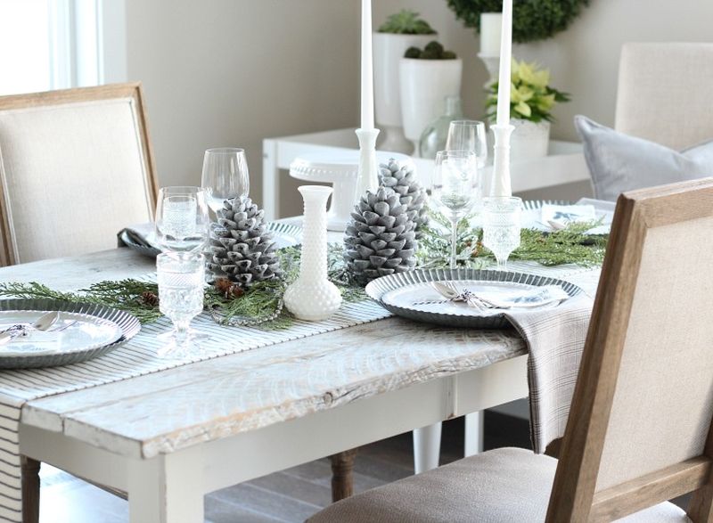 Christmas dining table with White candles, painted pine cones and napkins   