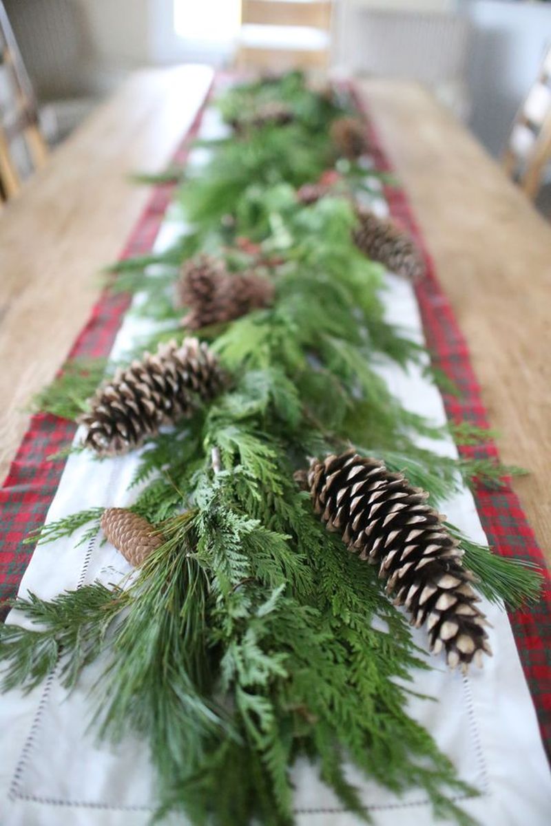 nature-inspired Christmas table decor with greenery, pepper berries and top it with pinecones