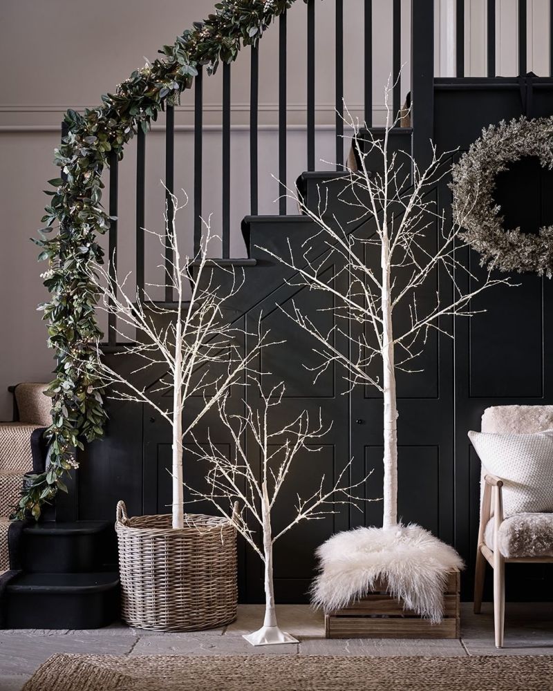 Faux white trees placed below stairs 