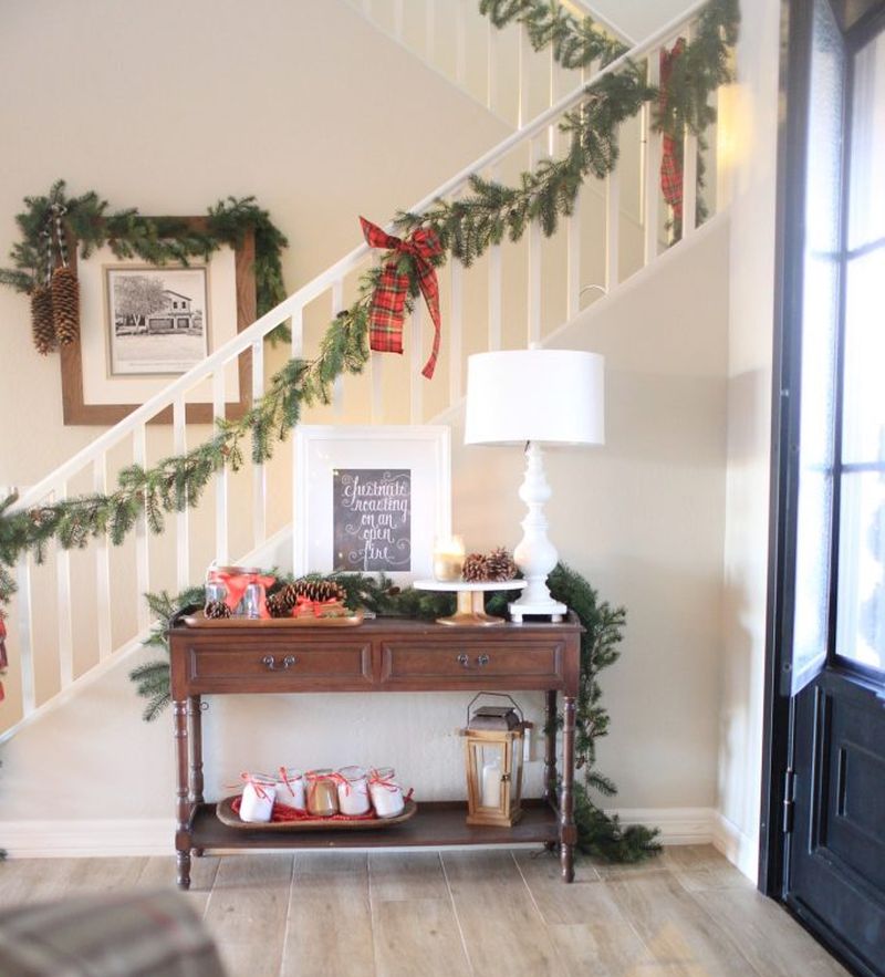 Staircase decorated with green garland and red ribbons 