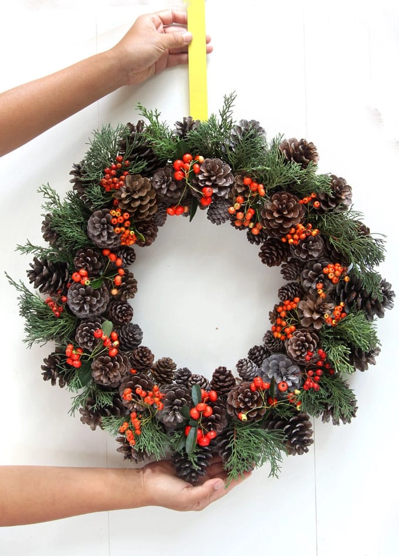 Christmas wreath craft with pine cones, foliage and berries 