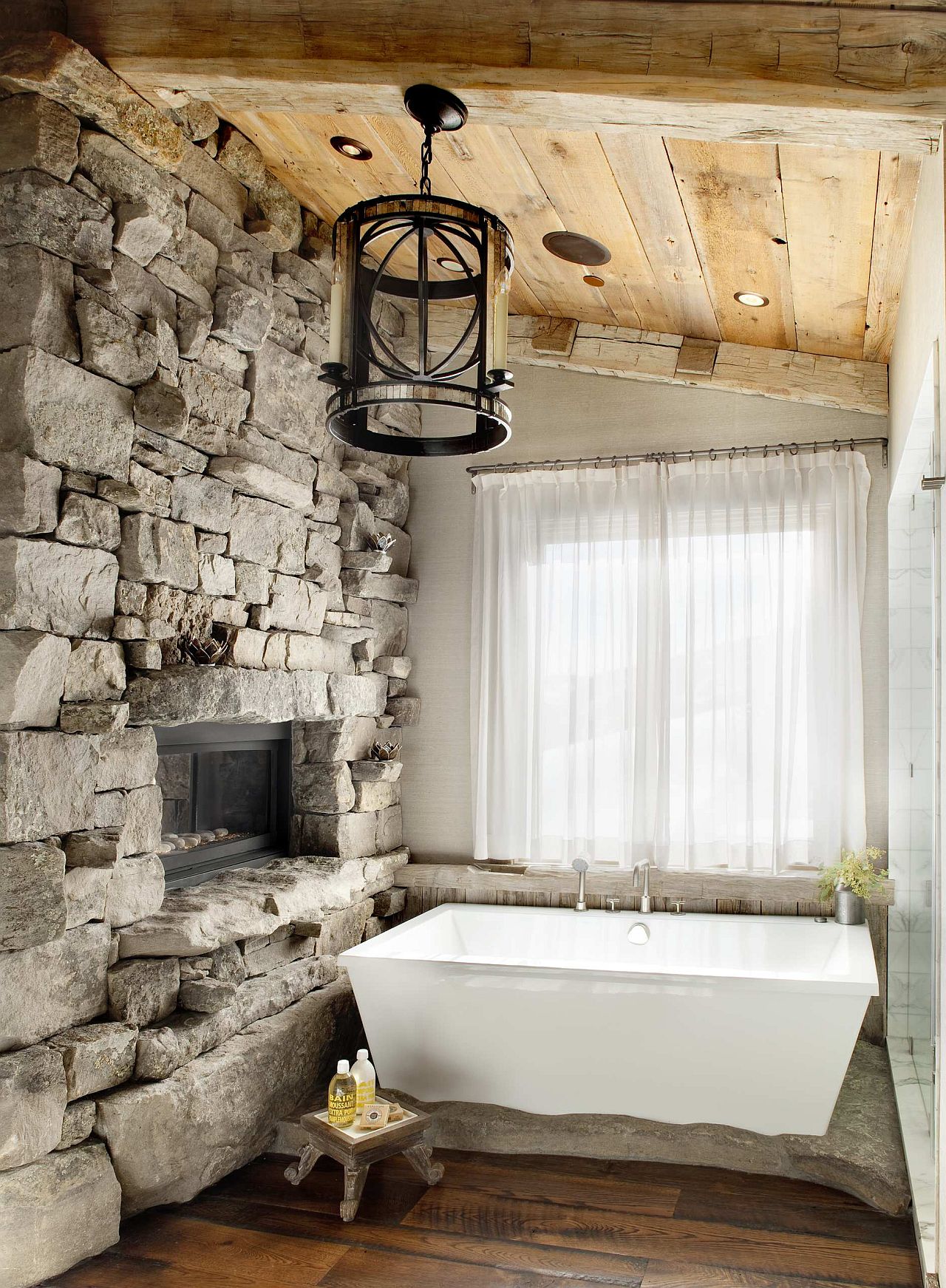 Stone walls and wooden ceiling add to the warmth of the bathroom fireplace