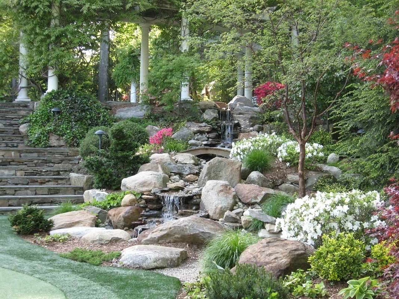 Gorgeous garden waterfalls along with a natural pond and flourishing flora