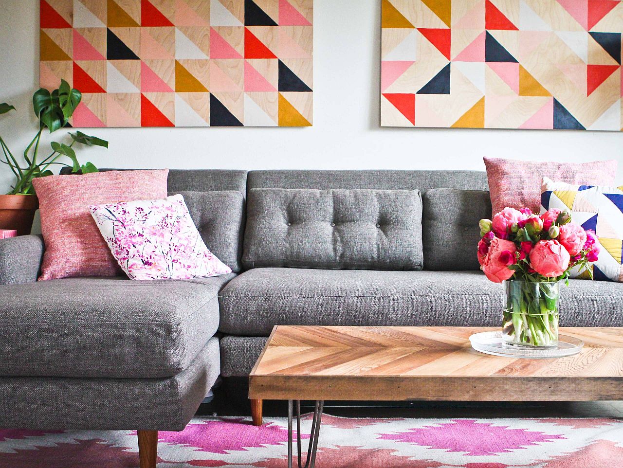 Wall art and rug bring different shades of pink to this living room with a gray couch