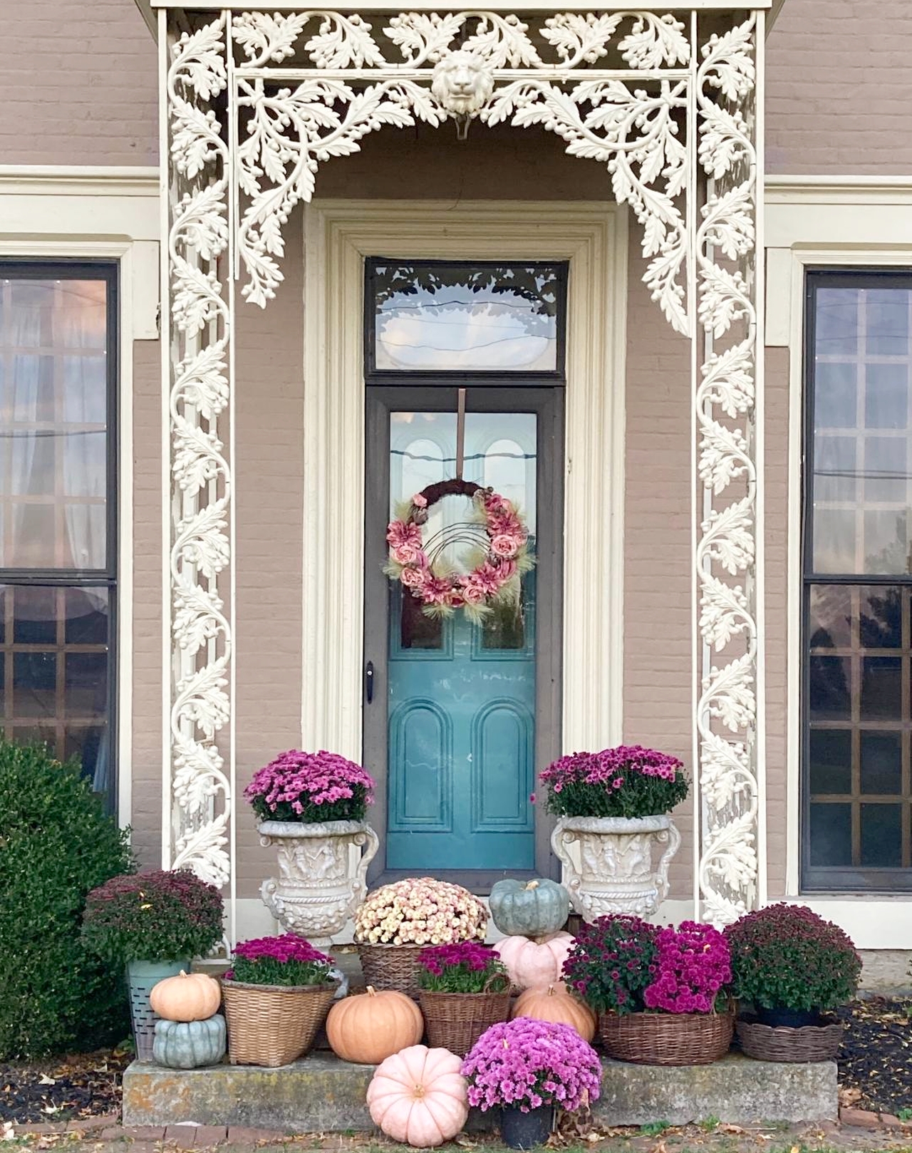 Potted chrysanthemums and painted pumpkins on porch