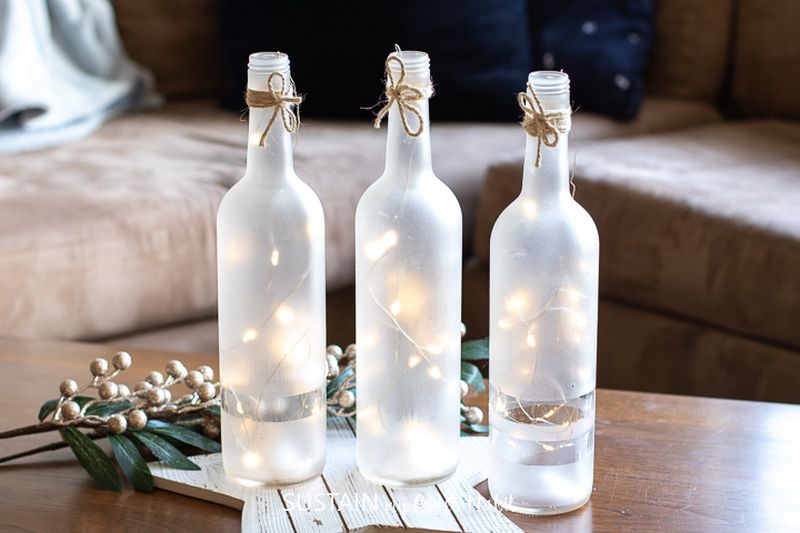 frosted wine bottle with greenery and lights  