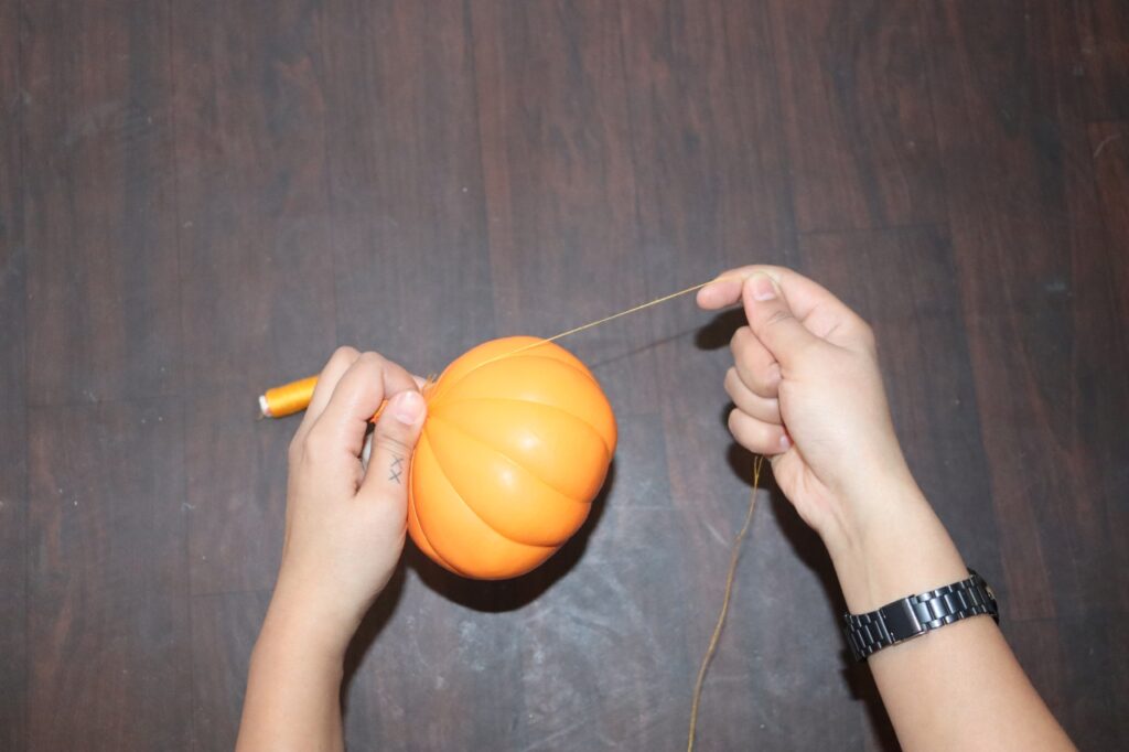 Wrap golden thread around the rounded balloon tightly to make pumpkins