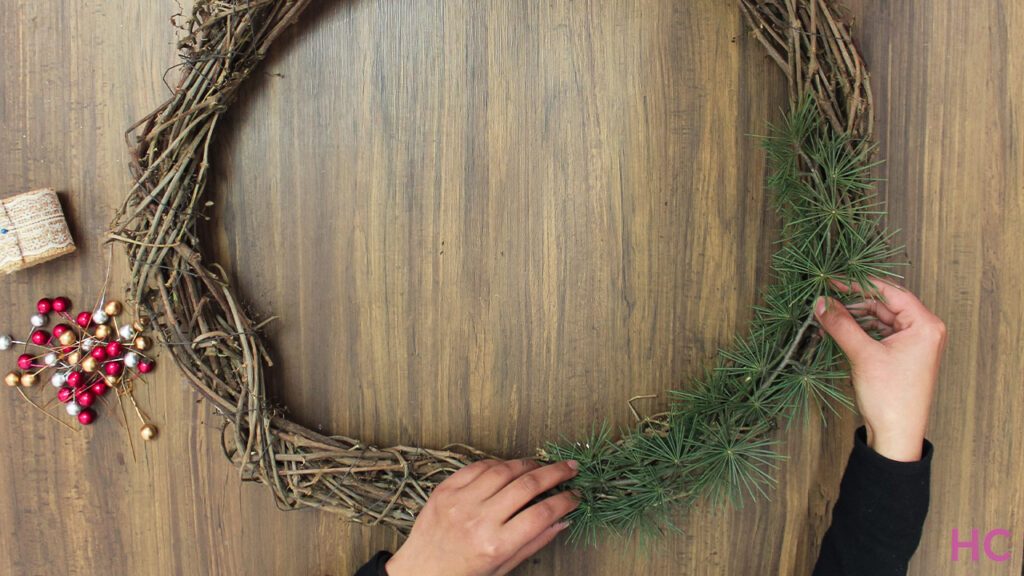 Add pine leaves inside the grapevine wreath base