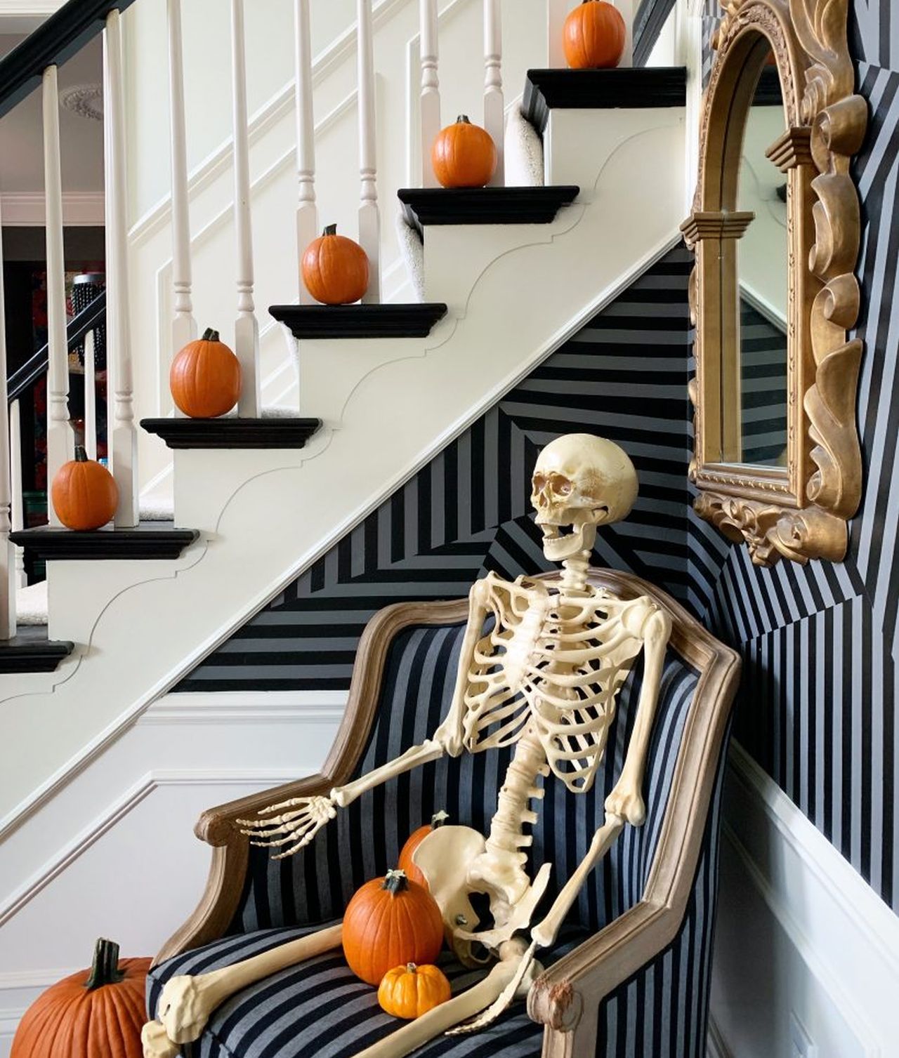 Halloween staircase decoration featiring skeleton lounging on chair