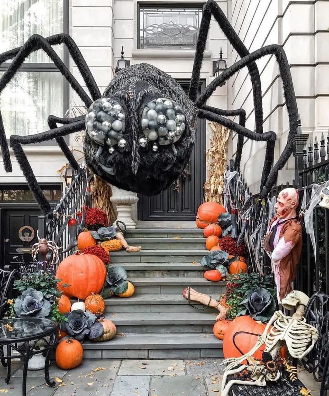 outdoor staircase halloween decoration with a giant spider, zombie, skeleton, cabbages and pumpkins