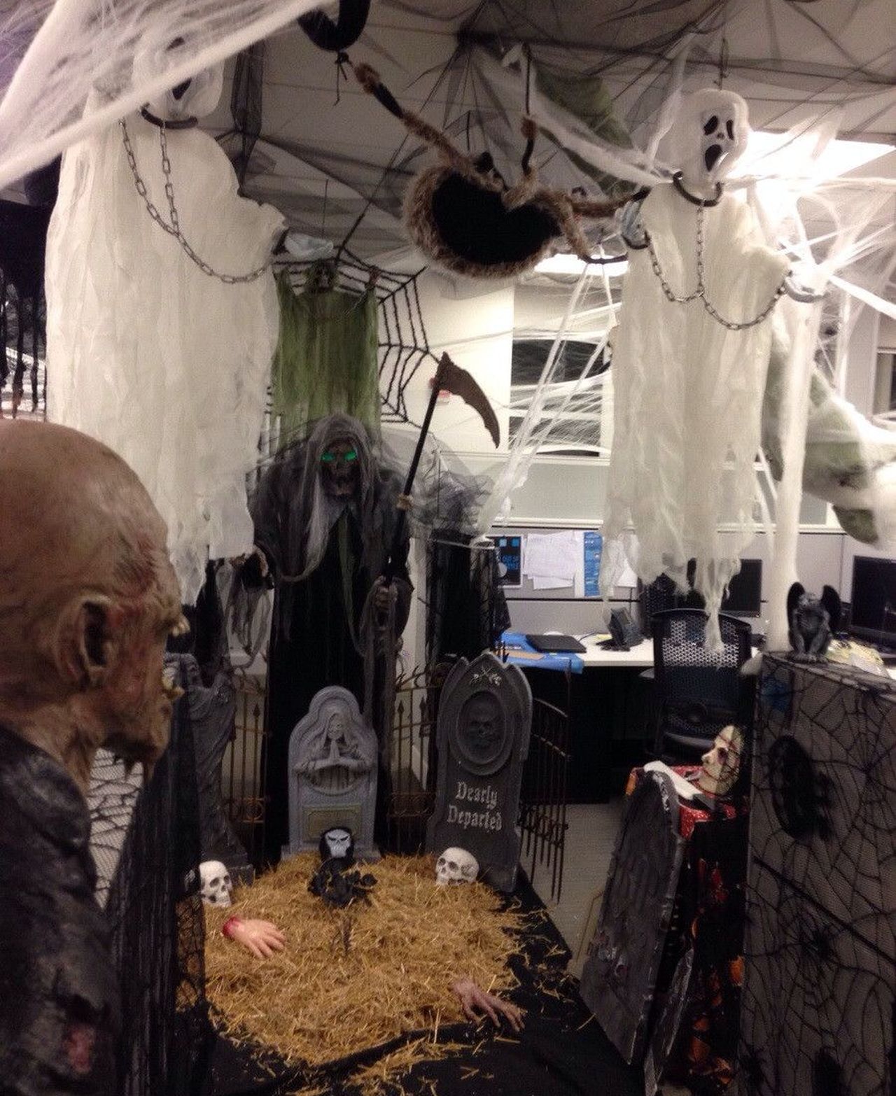 Office cubicle transformed into a graveyard with hanging ghosts and grim reaper figurine