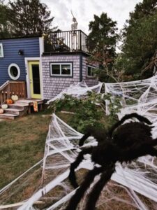 Tiny house halloween decor with skeleton on the rooftop balcony and cobwebs in front yard