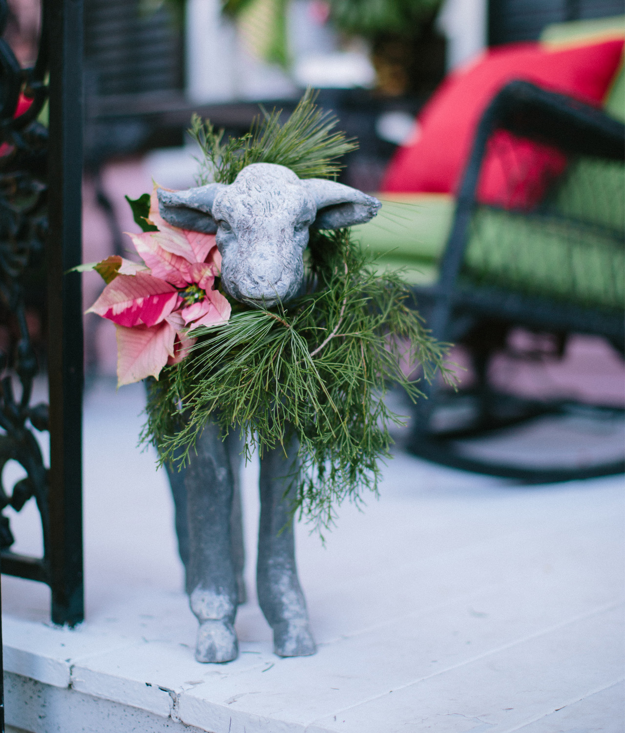 Cute lamb statue decorated with poinsettia wreath