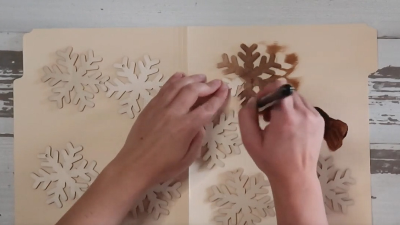 Applying stain on the wood-cut snowflakes