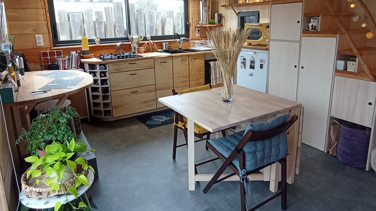 The spacious kitchen has wooden countertops, cabinets dining table and bar-style dining tabletop.