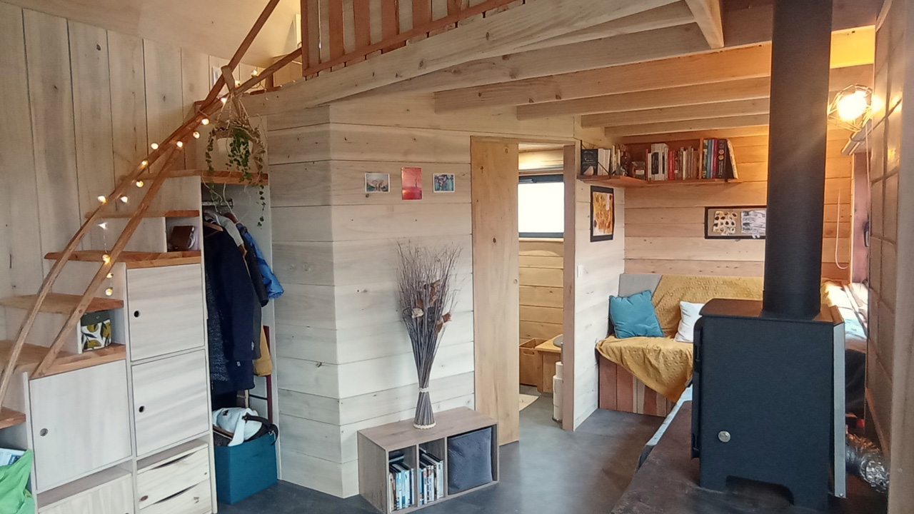 The interior of the tiny house has a woody, rustic charm and beautifully arched handrails look decorative.