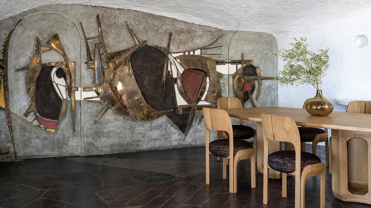 The oak furniture complements the stunning mural of the cave-like house.