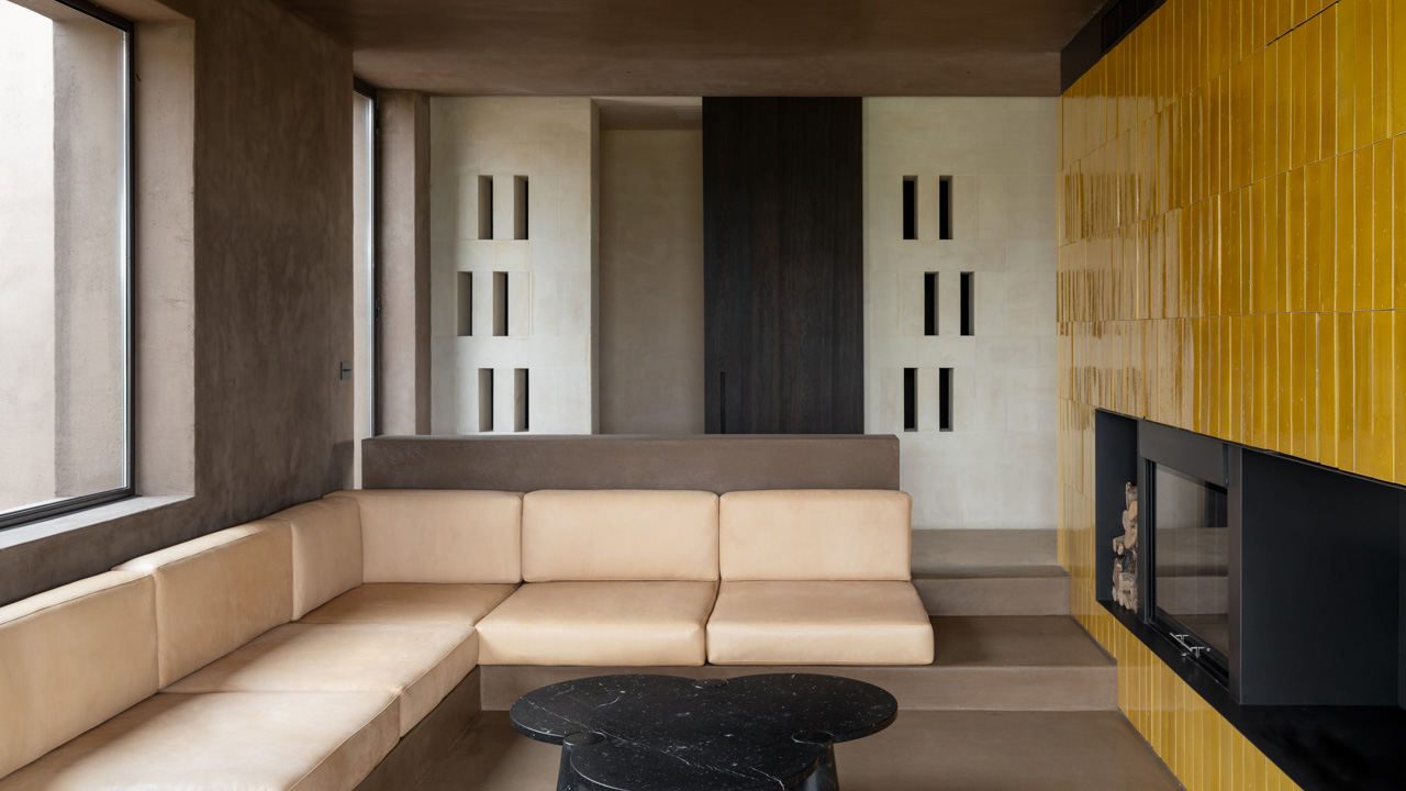 The spacious living space feature sofa and fireplace clad with yellow, glazed terracotta tiles