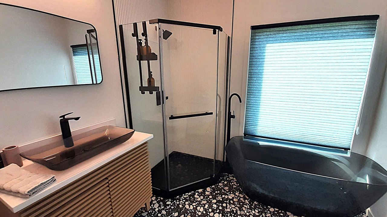 The full bathroom has striking Black outline on shower area, mirror and handles.