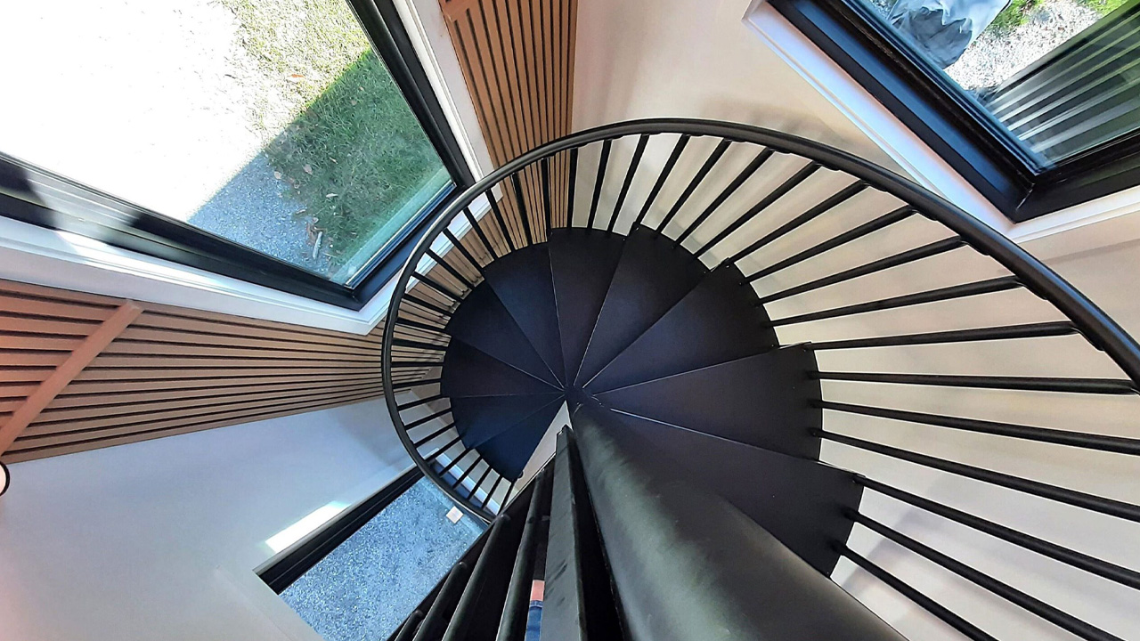 The black spiraled staircase serves as an a designer décor piece .