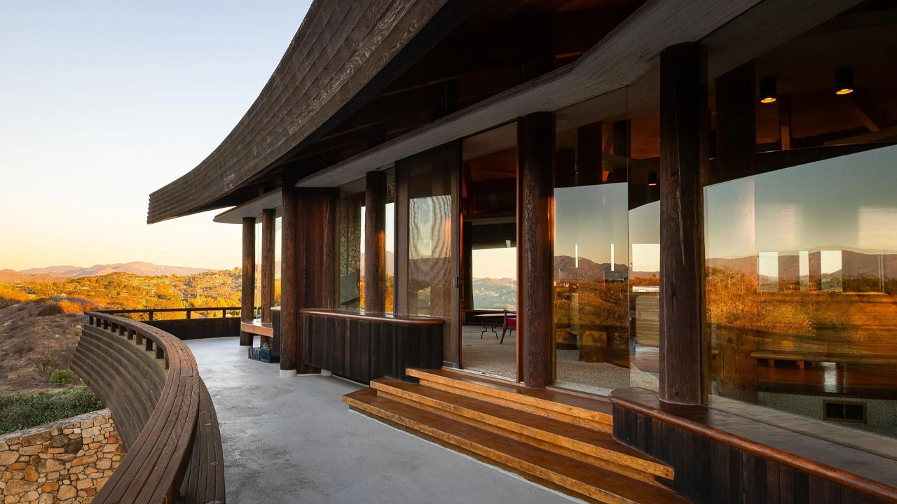 The floor to ceiling glazing is embedded within the wooden framework of the house