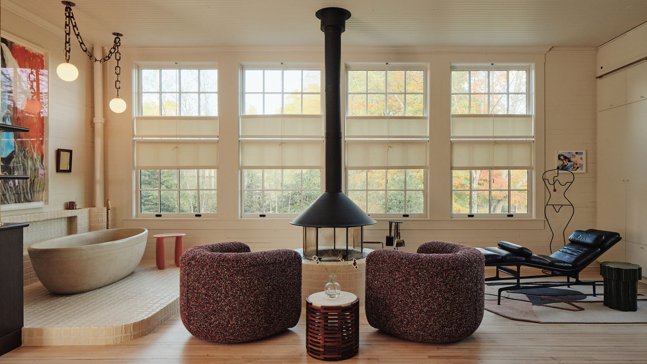 Rounded upholstered furniture and a bathtub in the primary bedroom of artist