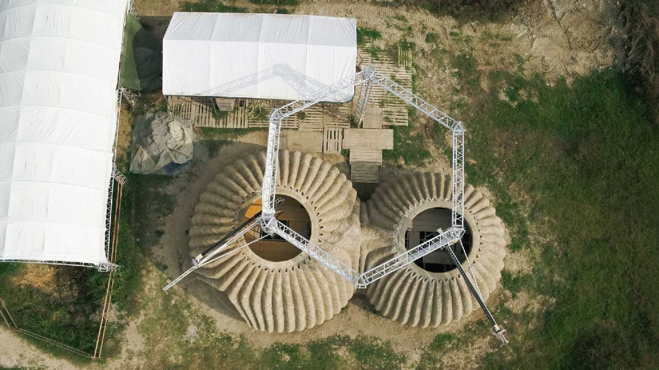 The large cranes building the prototype with 3D printing machines attached to them