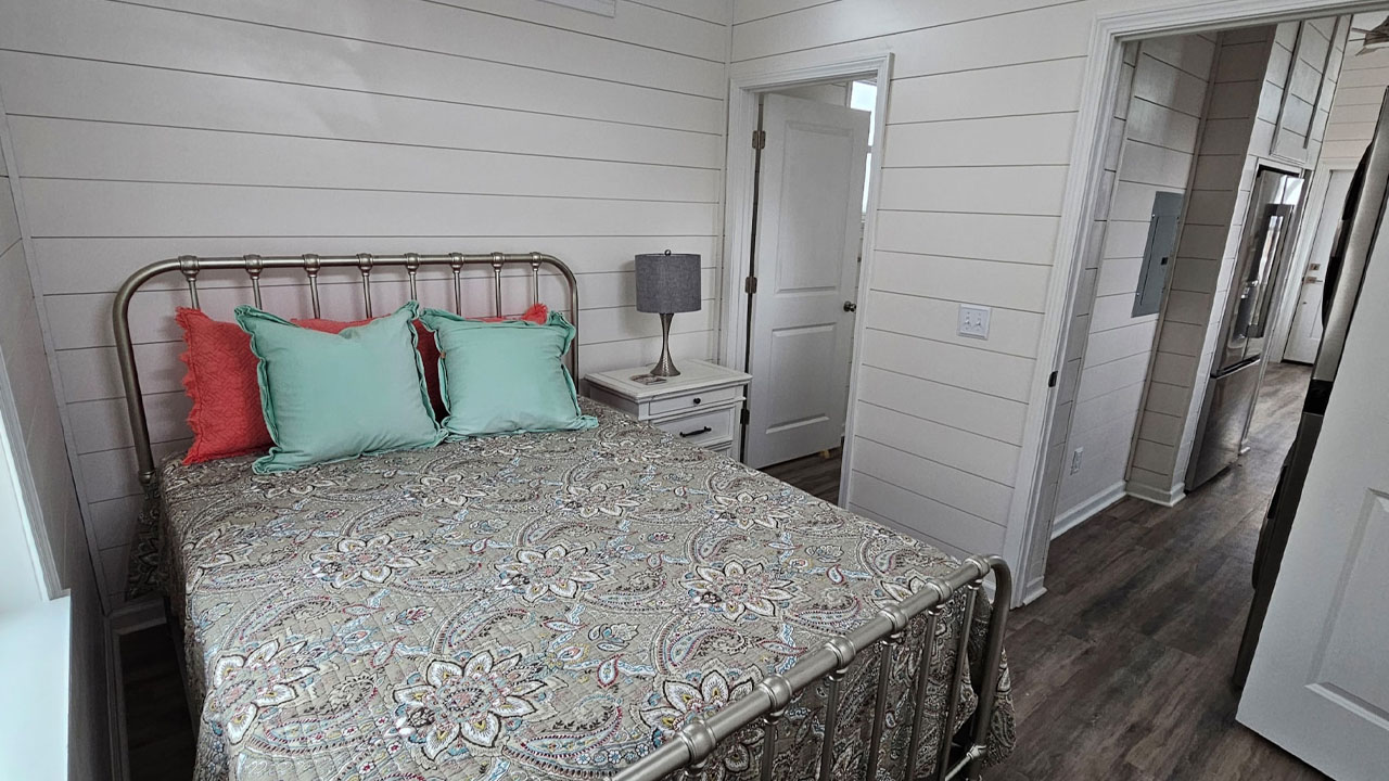 The cozy bedroom of customizable tiny house has en-suite bathroom