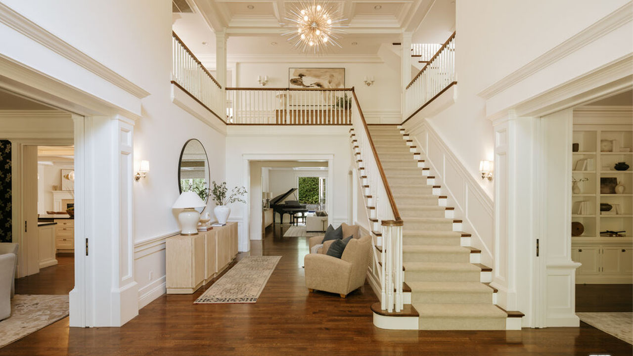 The dramatic sweeping staircase adorned with neutral carpet runner