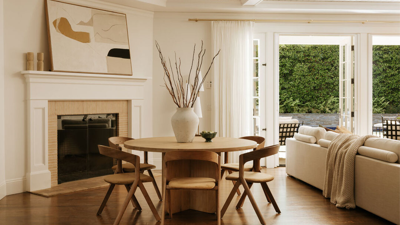 The round dining table nearby the white mantel and fireplace