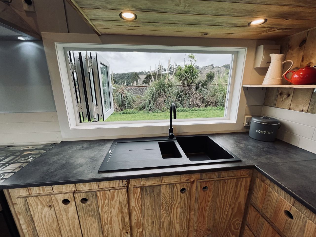 Maple Tiny House Features Overhang Shelf Above Kitchen for Extra Storage Smart Storage Hack