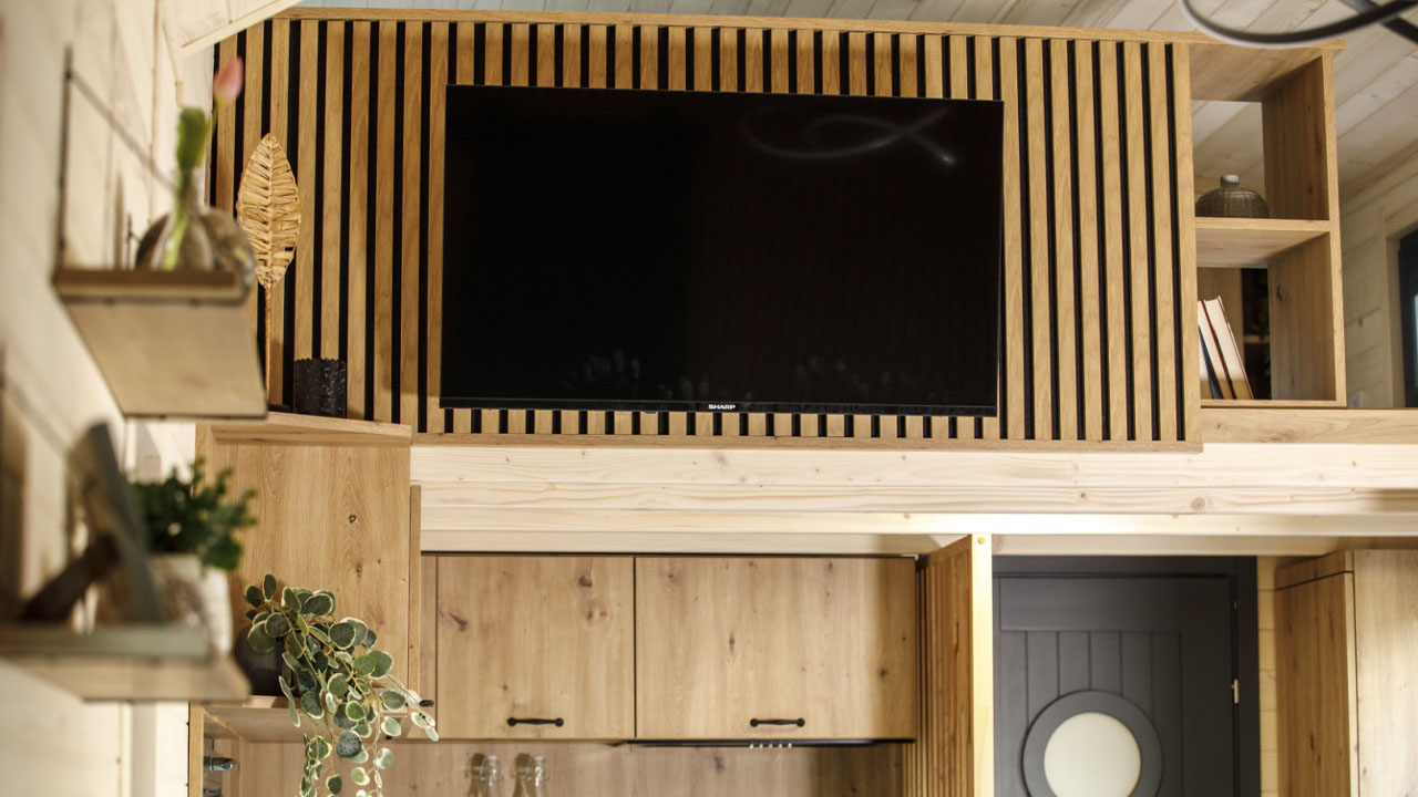 The large television mounted on the slatted wood panel