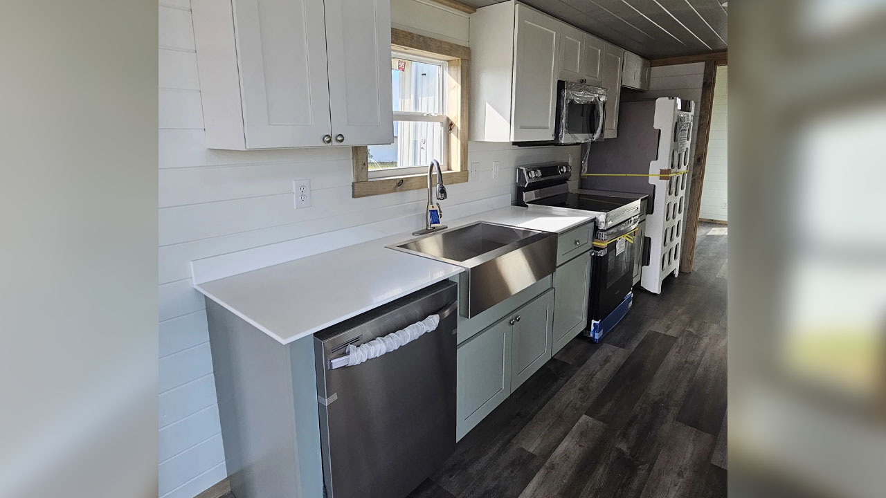 The linear kitchen has quartz countertop with flushed sink and gooseneck faucet