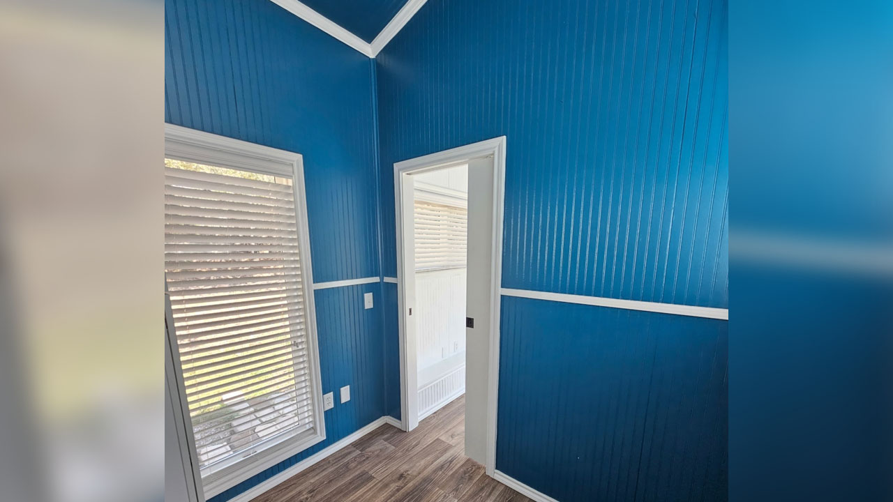 lovely white trims outline the deep blue-painted walls of the main-level bedroom
