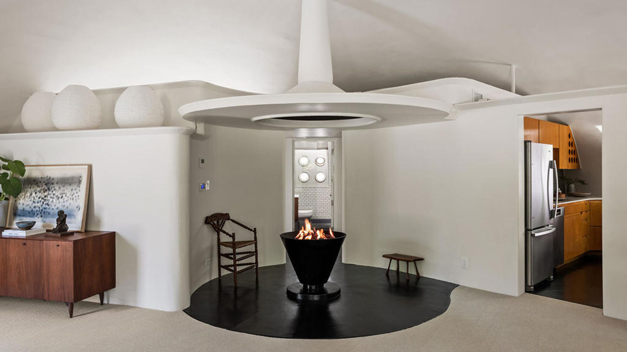 Sculptural fireplace sits between bathroom and kitchen