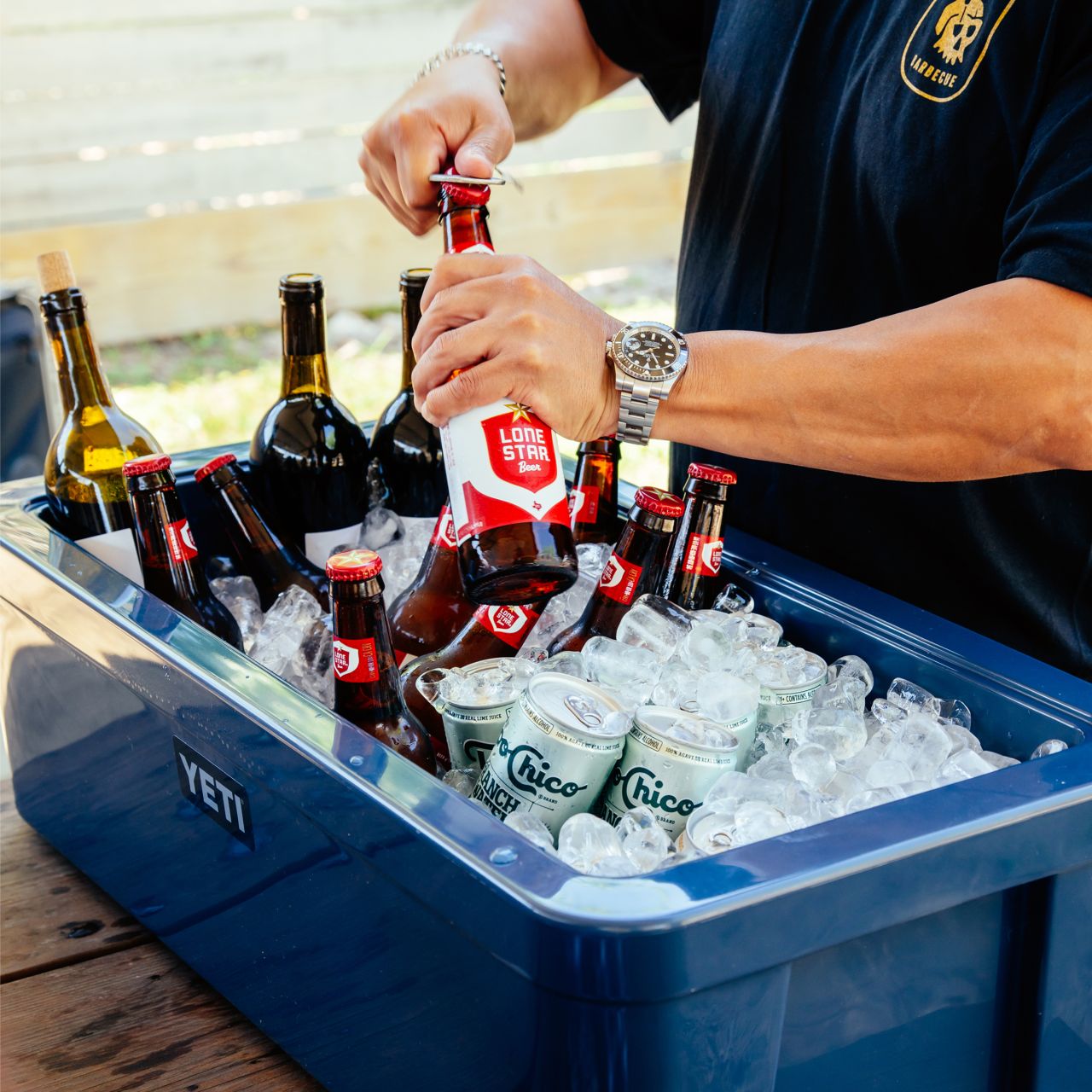 YETI Tank 30 Beverage Tub for Outdoor Parties - a person opening a beer bottle
